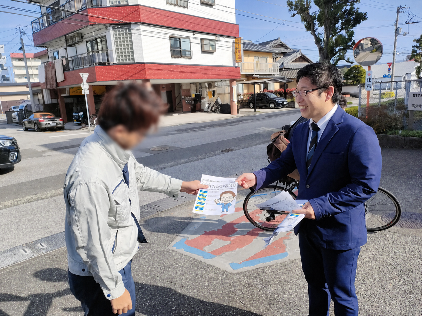 地域の方と対話しながら資料を手渡す楠目しんいちろう